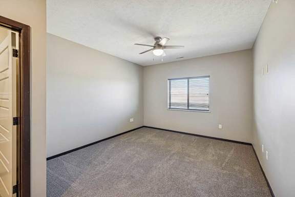 A room with a ceiling fan and a window with blinds.