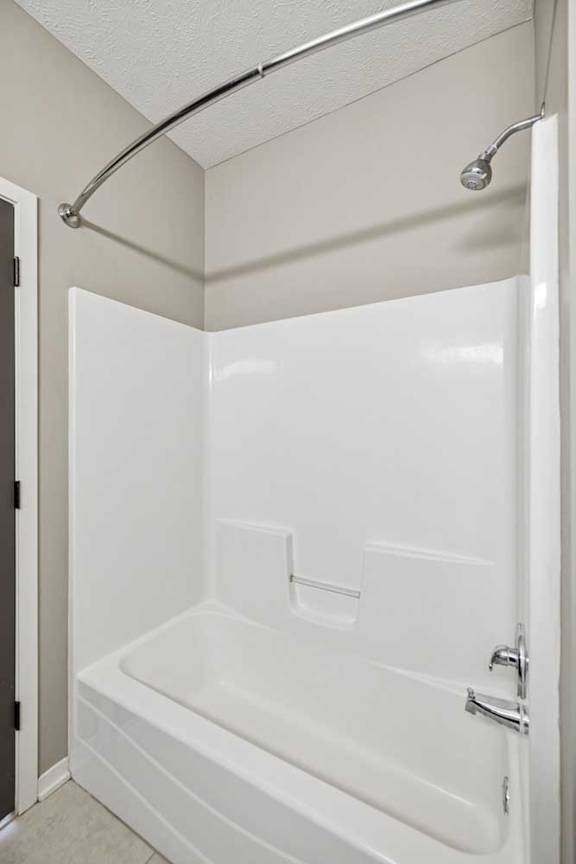 A tub shower with chrome fixtures and a curved shower curtain rod.
