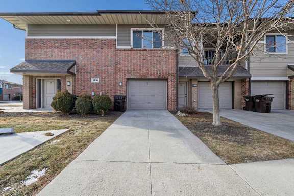 A brick apartment building with a garage door and a long driveway.