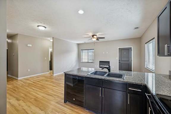 A kitchen peninsula with a sink, in front of a living room with hardwood-style flooring and an electric fireplace.
