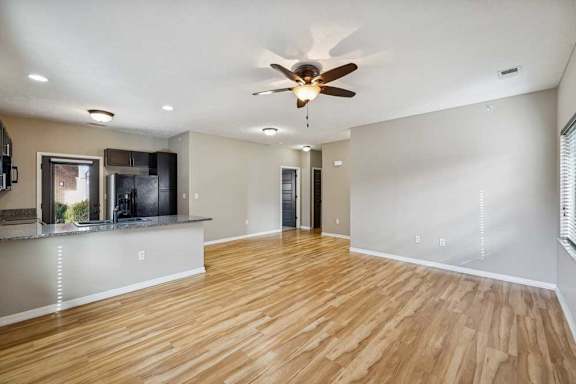 A living room with hardwood-style flooring open to a kitchen with granite countertops.