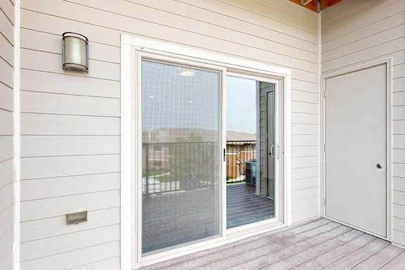 A covered balcony with a screen door and an outdoor closet.