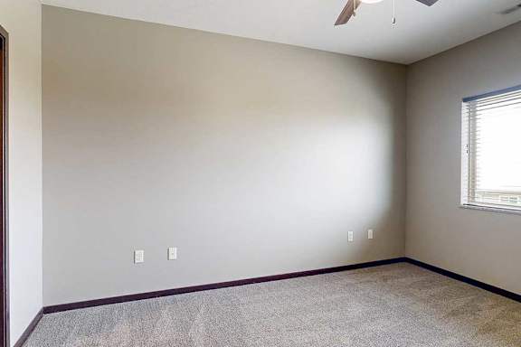 A carpeted primary bedroom with a window and a ceiling fan.