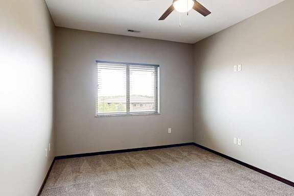 A bedroom with a ceiling fan and a window with blinds.