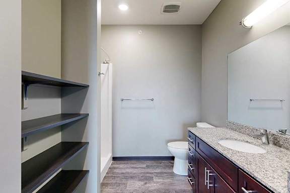 A bathroom with a wide vanity sink, large mirror, and built-in linen shelves.