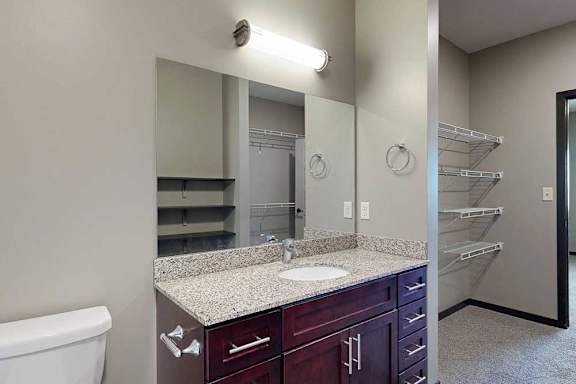 A vanity sink with a granite countertop and mounted mirror.