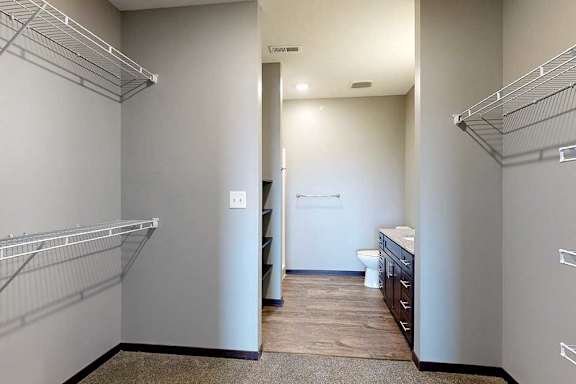 A walk-in closet with shelves and an attached bathroom.