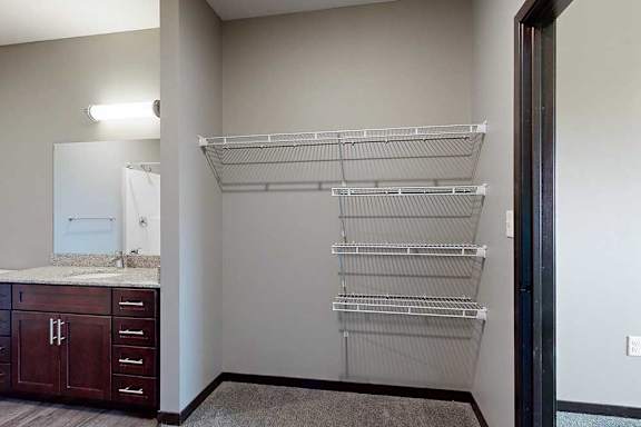 A walk-in closet connected to the attached bathroom with built-in wire shelving.