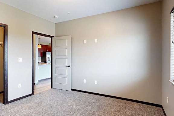 A bedroom with a carpeted floor and a door open to the hallway.