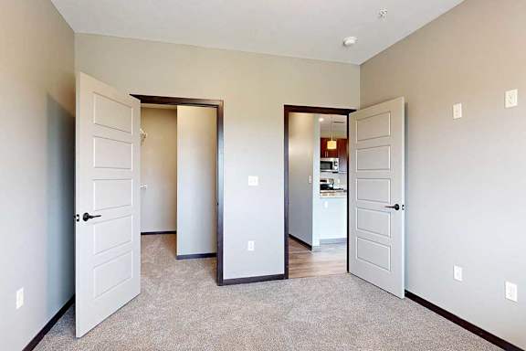 A bedroom with a door to a large walk-in closet, and a door leading to the hallway.