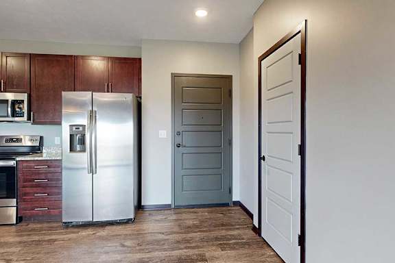 A dark grey front door with a coat closet to the right, and a modern kitchen to the left.
