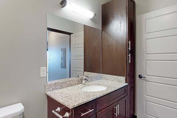 A bathroom with a sink, mirror, and tall storage cabinet.