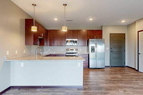 A kitchen opening into a front entryway with wood-style flooring.