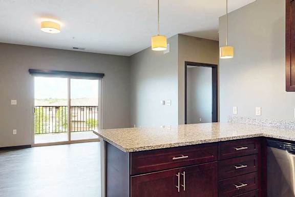 A view of the open layout connecting the living room and kitchen, with a peninsula countertop in the kitchen.