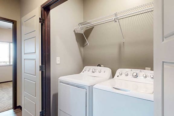 A laundry area with a side-by-side washer and dryer, with overhead storage.
