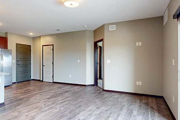 A spacious living area with neutral walls and wood-style flooring.
