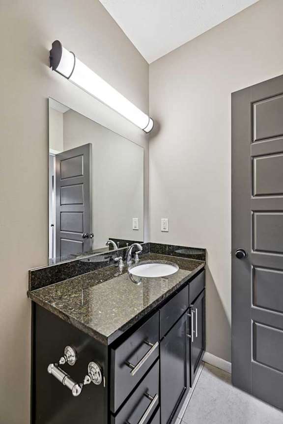 A bathroom with a sink, mirror, and black cabinets.