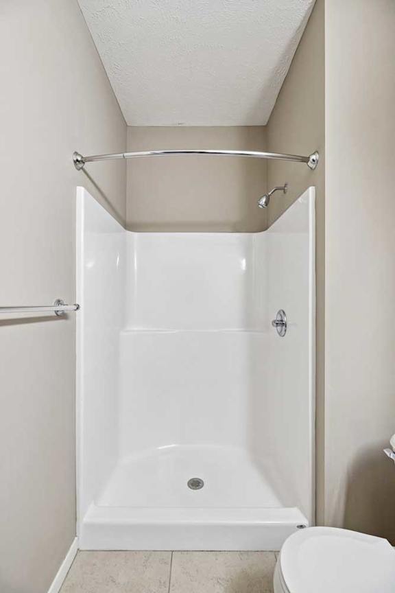 Bathroom featuring a walk-in shower with white surround walls and a curved curtain rod.
