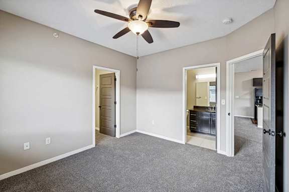 A room with a ceiling fan and a grey carpet.