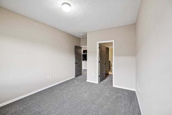 A room with a grey carpet and a door leading into the bathroom