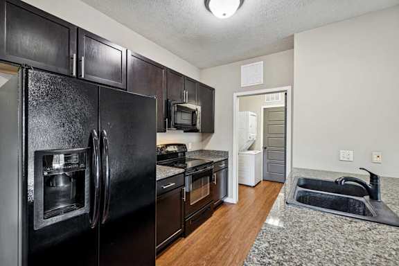 A kitchen with black appliances and wooden cabinets.
