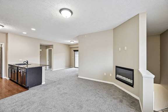 A spacious living room with a fireplace and a kitchen area in the background.