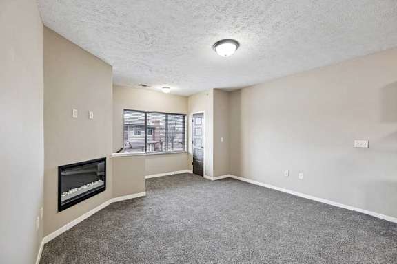 A living room with a fireplace and carpeted floor.