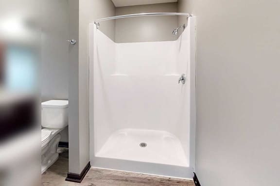A bathroom with a walk-in shower with chrome finishes and a curved curtain rod.