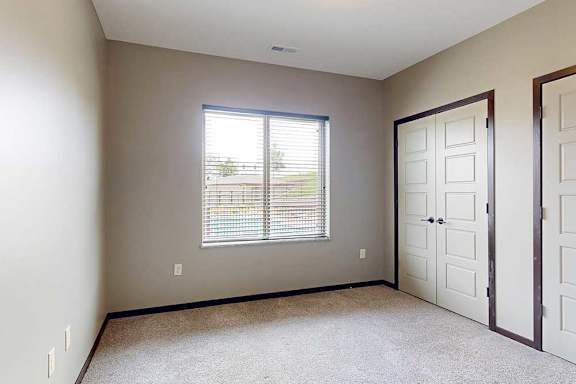 A bedroom with two closed side-by-side closets, and a large window.