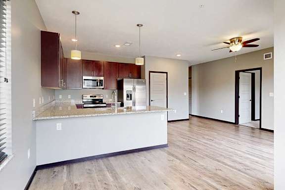 An open concept living room next to a kitchen with wooden cabinets and a peninsula countertop.