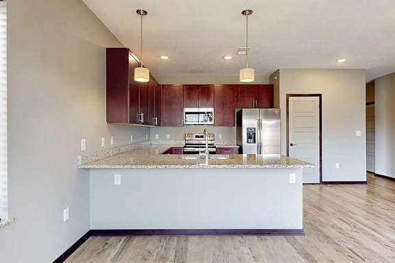 A modern kitchen with wooden cabinets, granite counters, and stainless steel appliances.