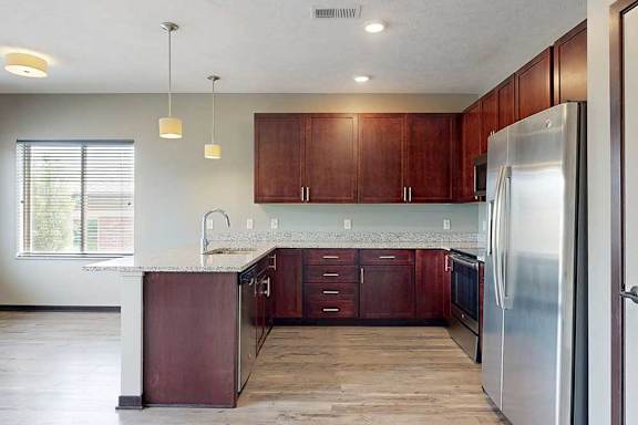 A modern kitchen with wooden cabinets, granite counters, and stainless steel appliances.