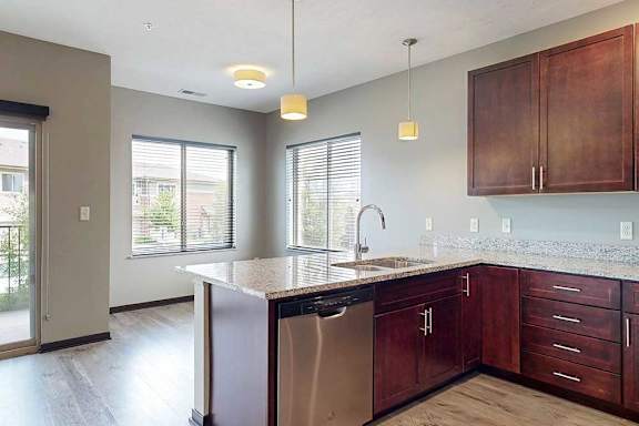 A kitchen peninsula with a sink and dishwasher in front of a dining area.