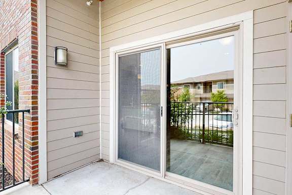 A balcony with a metal railing, and a sliding glass door to the living room.