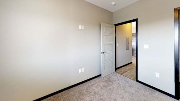 A room with a carpeted floor and a white door.