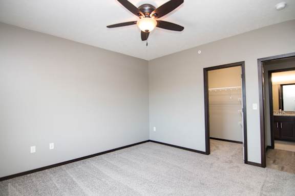A room with a ceiling fan and carpeted floor.