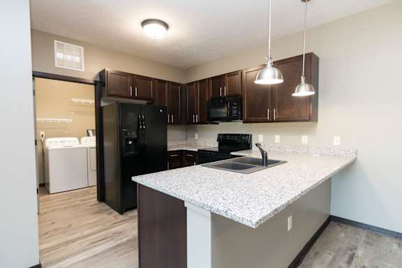 A kitchen with black appliances and brown cabinets.