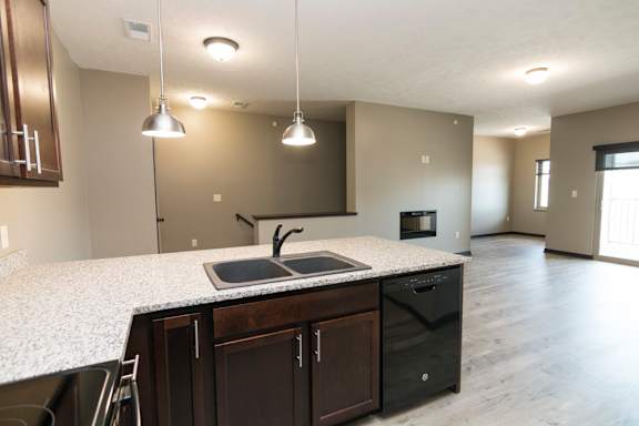 A kitchen with a granite countertop and dark brown cabinets.