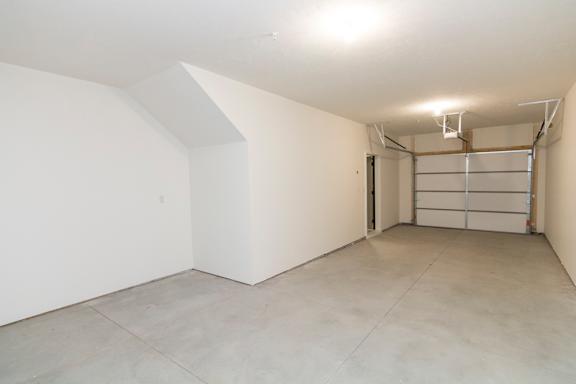 A large empty room with a white ceiling and a door on the right side.
