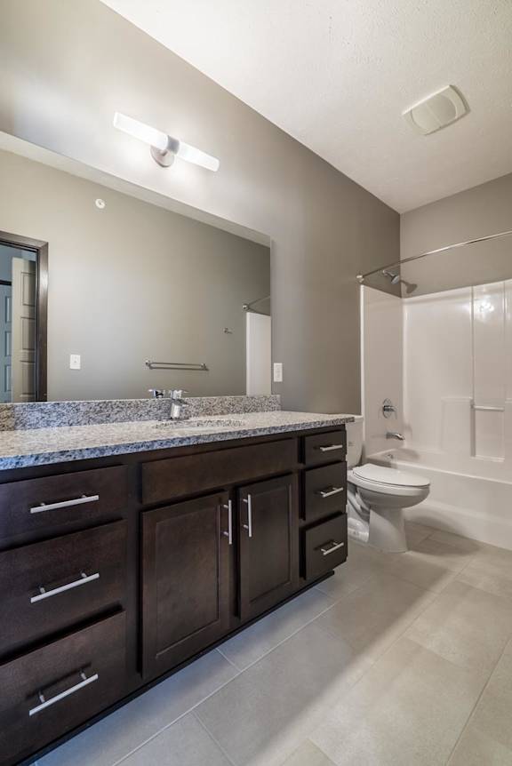 A bathroom with a sink, toilet, and a mirror.
