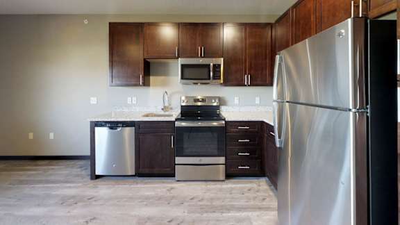 a kitchen with dark wooden cabinets, granite countertops, and stainless steel appliances