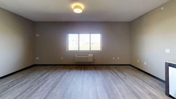 a living room with hardwood flooring, a large window, and an in-home A/C & heating system