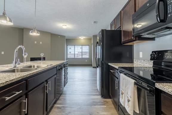 A kitchen with black appliances and a marble countertop.