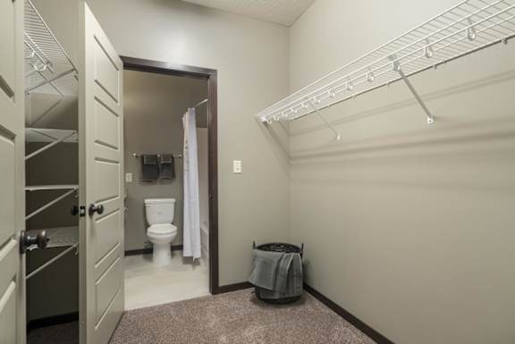 A bathroom with a toilet, a shower, and a towel on the floor.