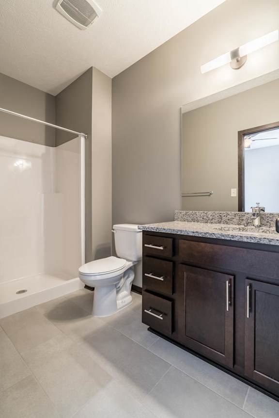 A white toilet sits in a modern bathroom with a marble countertop and a large mirror.
