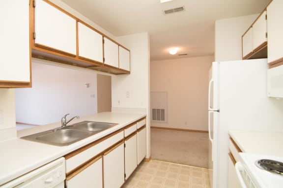 a kitchen with white cabinets and a sink and a refrigerator