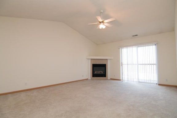 an empty living room with a ceiling fan and a fireplace