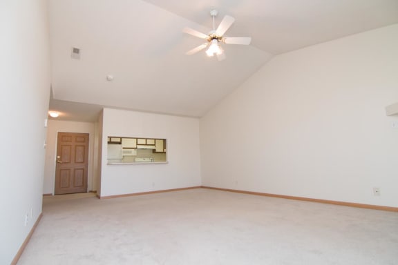 an empty living room with a ceiling fan