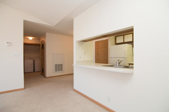 an empty living room and kitchen with a sink and refrigerator