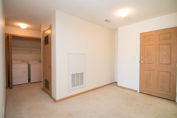 an empty living room with a door to a laundry room